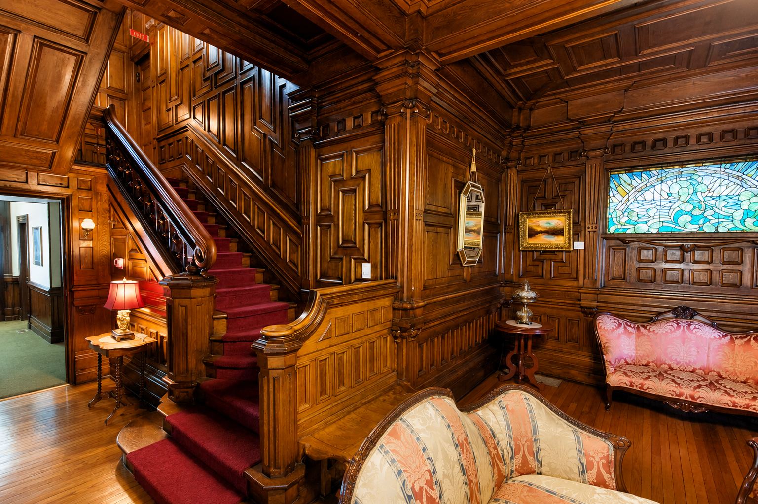 The grand oak foyer and staircase at Cedar Crest Inn, with a Tiffany stained glass window