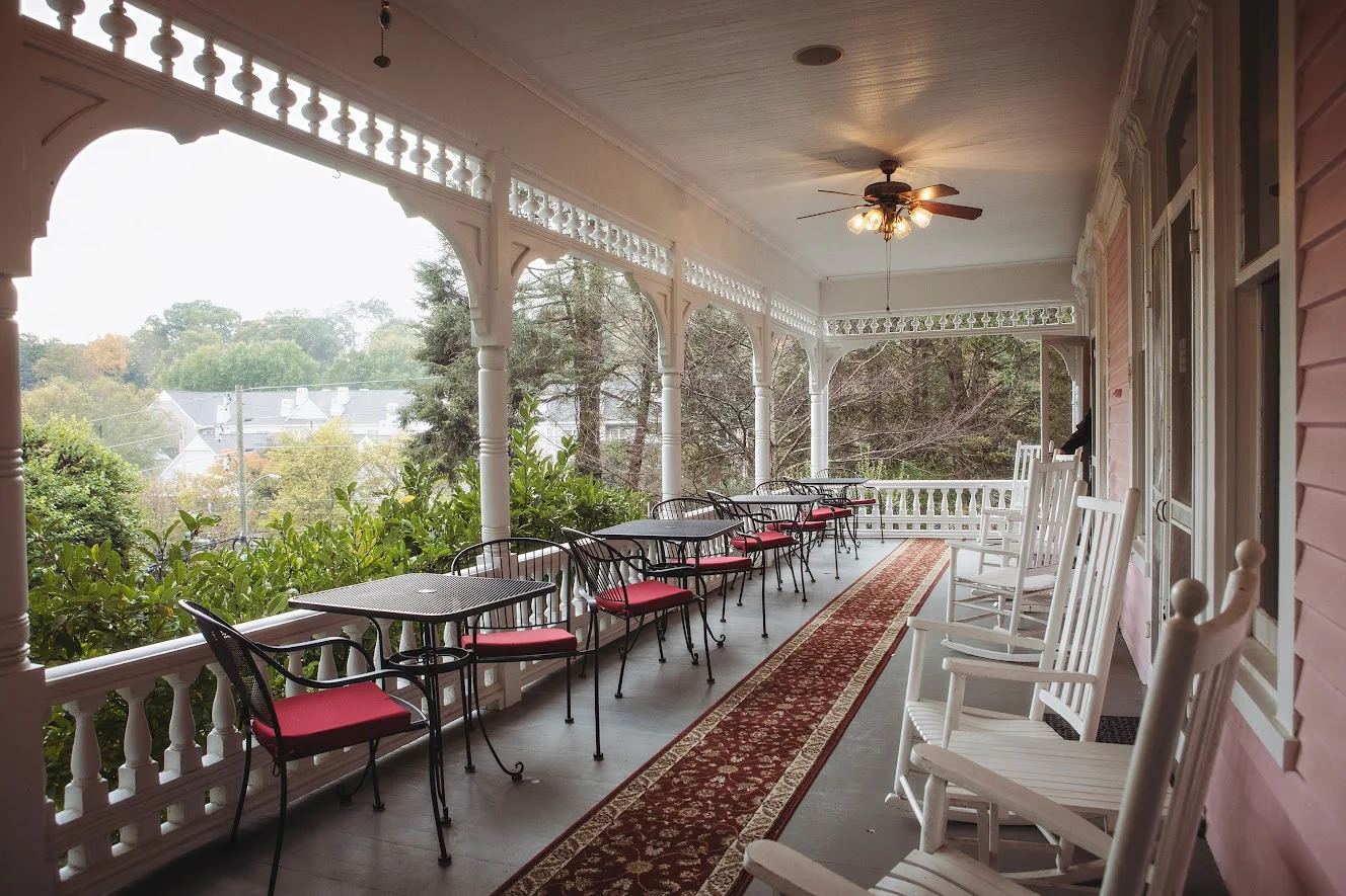 The wraparound porch at Cedar Crest Inn with rocking chairs and set tables